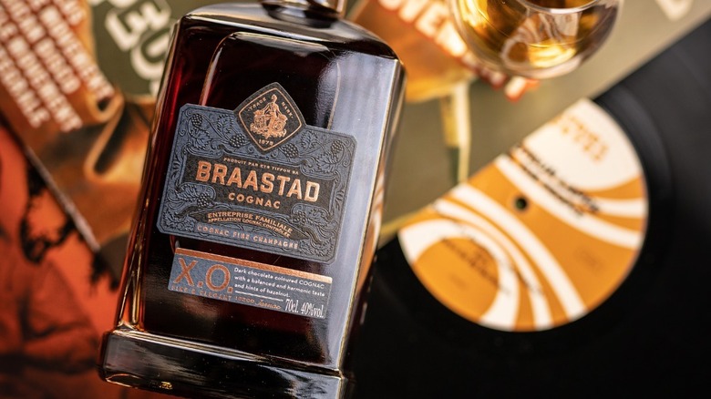 A bottle of Braastad XO posed to the camera with a blurred vinyl record in the background