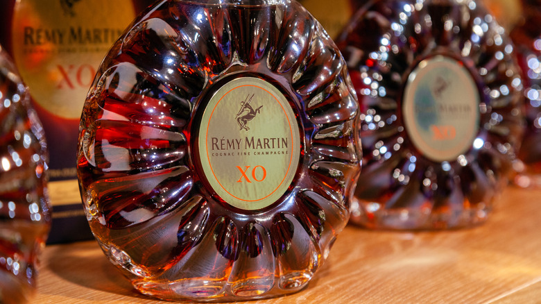 A close up of a bottle of Rémy Martin XO with blurred bottles surrounding it