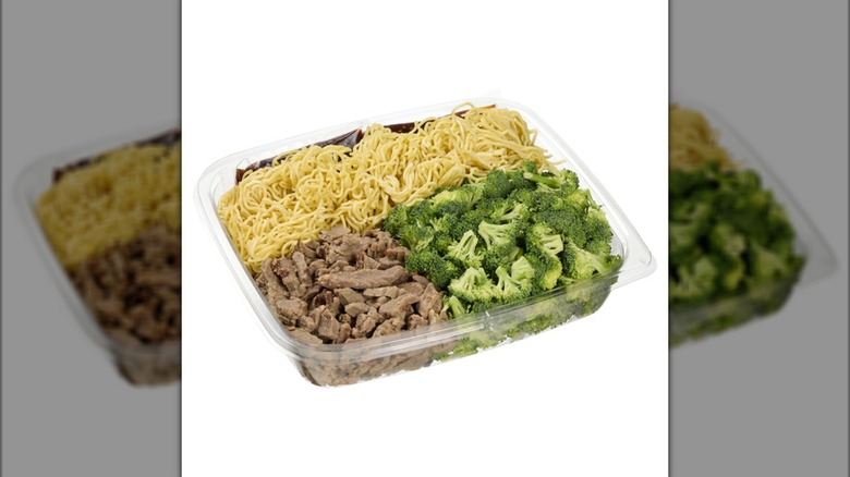 Kirkland Signature beef and broccoli with noodles and packages of stir fry sauce, all in a plastic container.