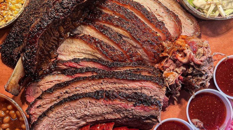 Assorted BBQ platter with brisket, ribs, sauces, and sides