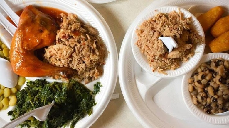Two plates with assorted BBQ and sides including chicken, collard greens, and black eyed peas