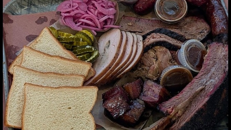 BBQ platter with bread, pickles, onions, turkey, ribs, brisket, sausage, and sauce