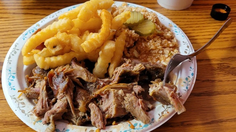 Plate of pulled pork with fries, pickles, and slaw