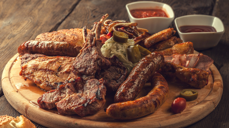 Assorted BBQ meats on wooden tray with sauces