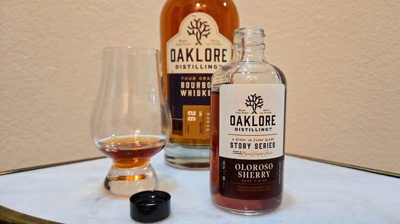 Big and small bottle of Oaklore Story Series oloroso sherry cask bourbon and glass