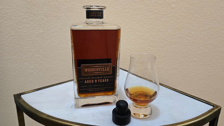 Woodinville 9-year-old bourbon bottle on a table with a glass on the side