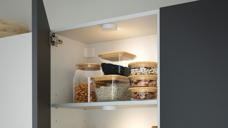Upper kitchen cabinet with pantry staples and a light