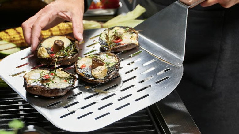 Four roasted mushroom caps on a stainless steel pizza peel