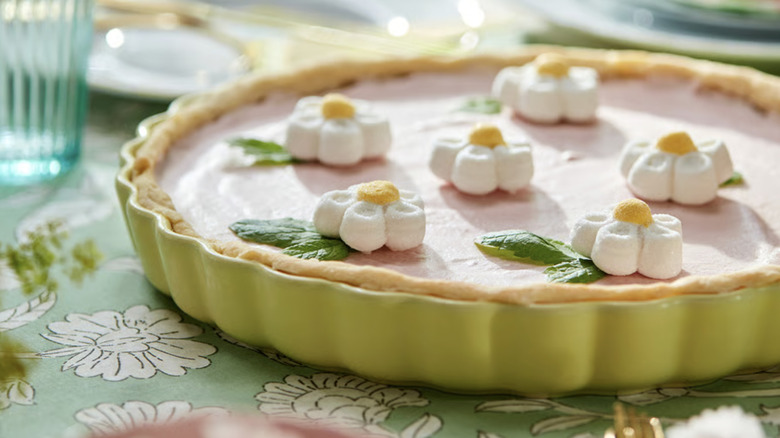 Pie decorated with edible daisies, displayed in a yellow pie plate