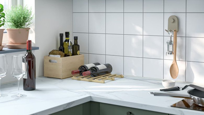 A corner of a kitchen counter displaying several wine bottles and two wine glasses