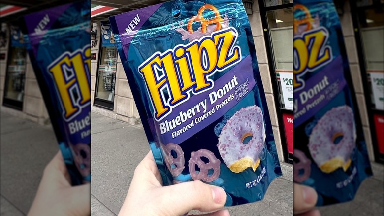 Hand holding a purple bag of blueberry-flavored Flipz pretzels