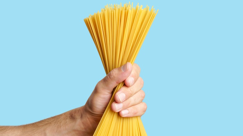 Hand holding dry spaghetti