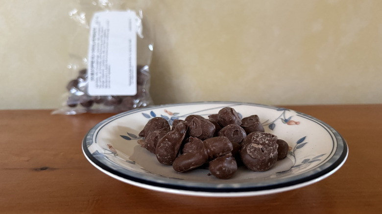 Double dipped milk chocolate peanuts on plate in front of bag