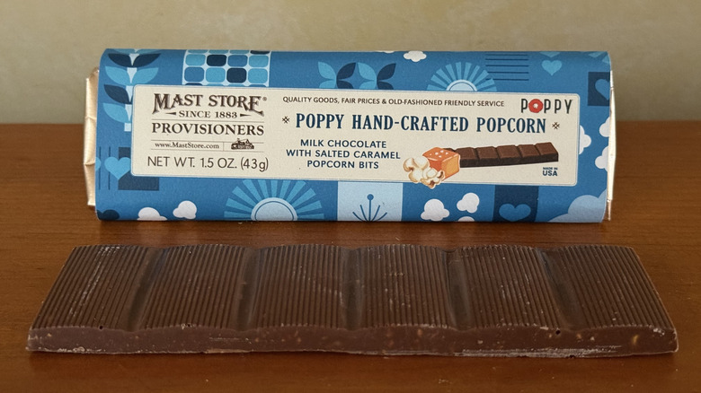 Poppy hand-crafted popcorn chocolate bar in front of wrapper on wooden table