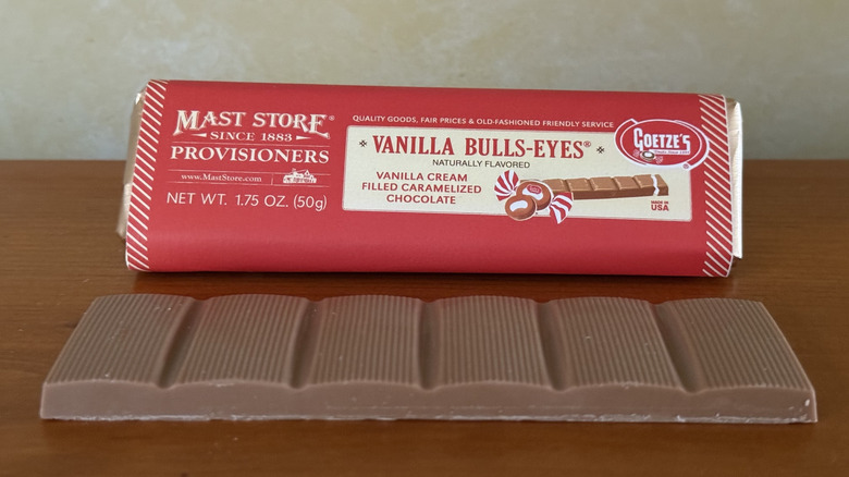 Chocolate bar in front of wrapper on wooden table