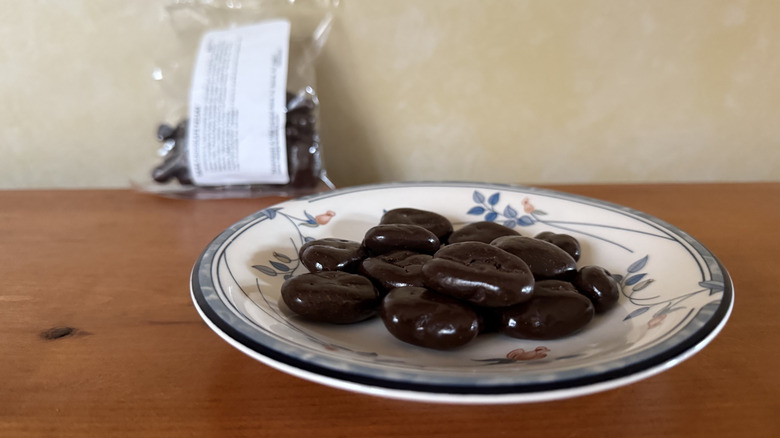 Chocolate covered pecans on plate in front of bag