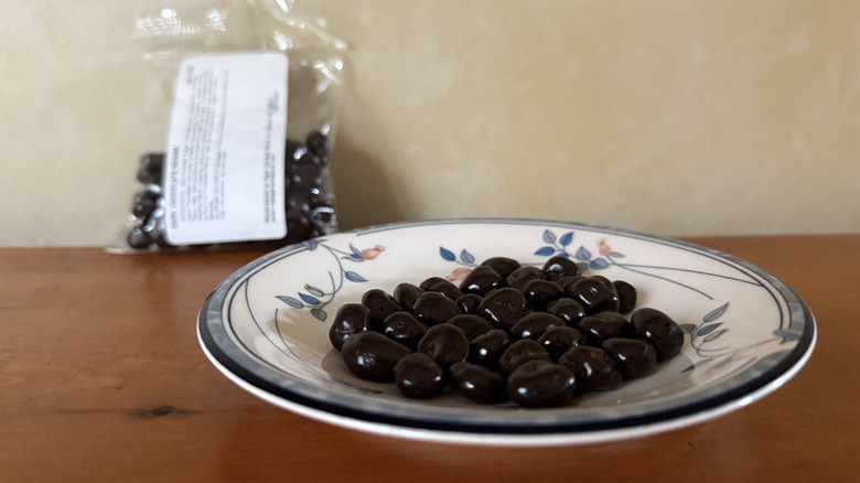 Chocolate covered raisins on plate in front of bag