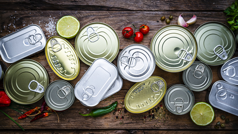 Assorted canned foods surrounded by tomatoes and limes