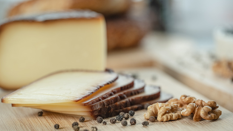 Smoked cheese sliced in a stack on a wooden cutting board