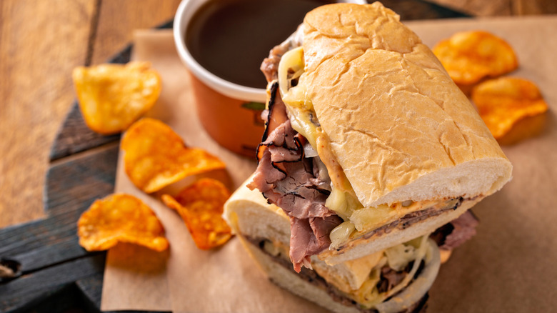Cup of soup and a sub sandwich on parchment paper with chips