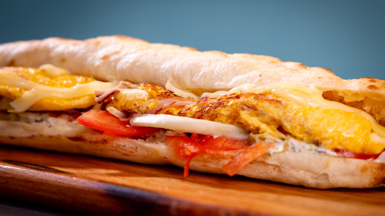 Breakfast submarine sandwich on a wooden cutting board