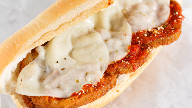 Eggplant parmesan submarine sandwich on a beige background