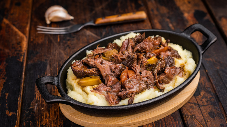 A plate of braised beef cheek over mashed potatoes