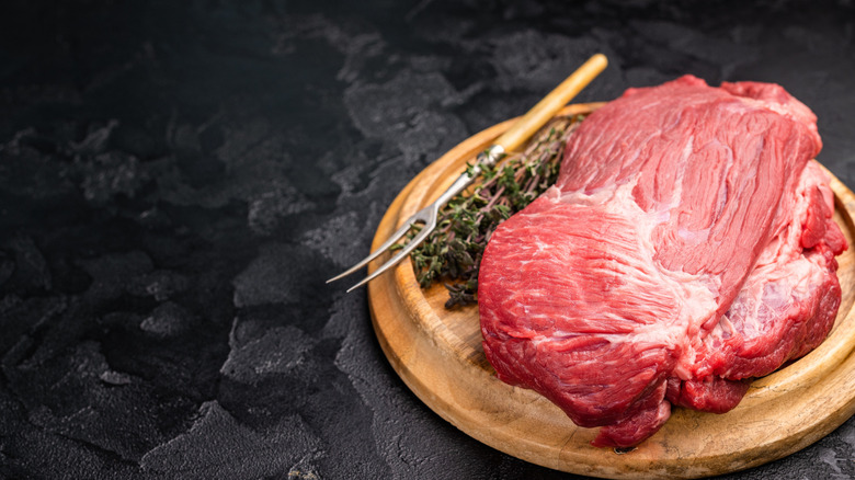 Raw piece of silverside beef on a wooden plate