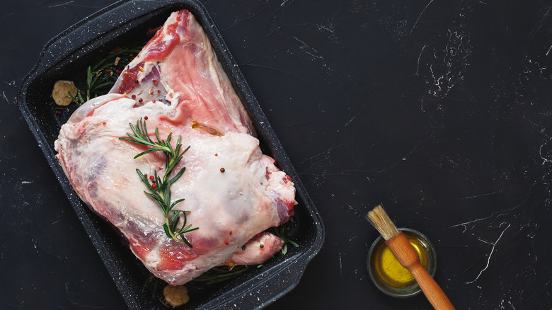 Raw lamb shoulder with garlic and rosemary in a pan