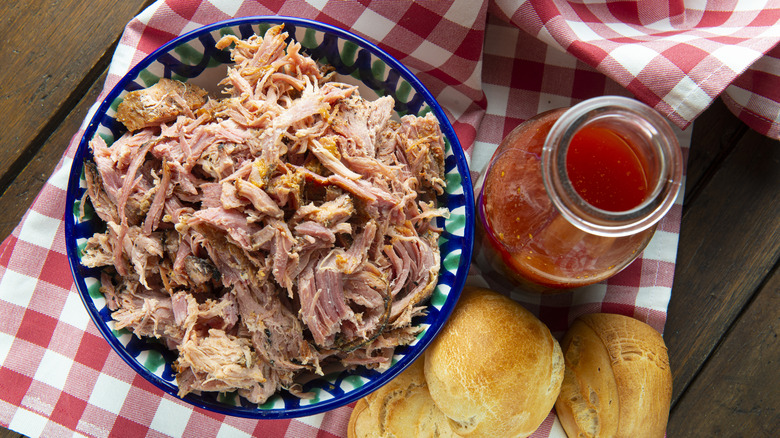 Pulled pork with vinegar sauce with rolls on red and white towel