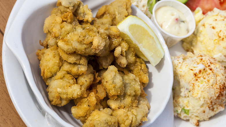 Deep fried clams with lemon wedge on plate