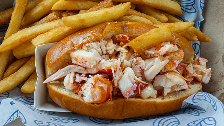 Stuffed lobster roll with fries on plate