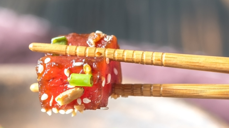 Cube of poke with chopsticks holding the fish on the west coast