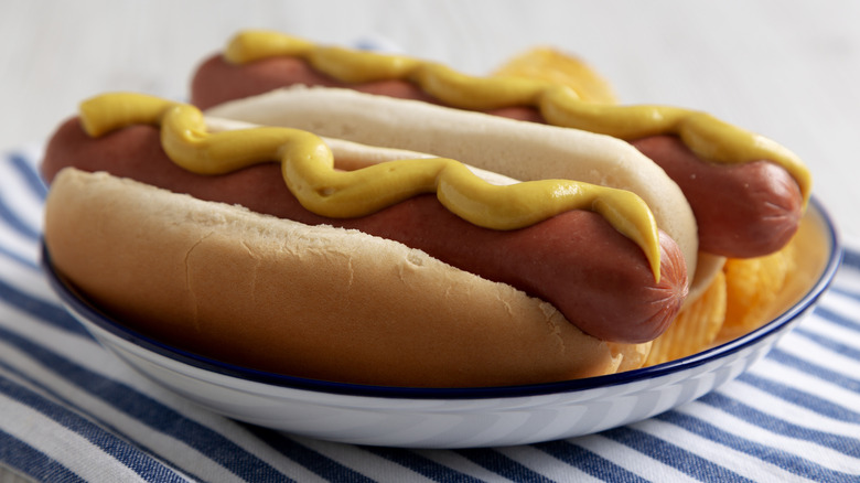 hot dogs on a white plate on blue and white striped table cloth