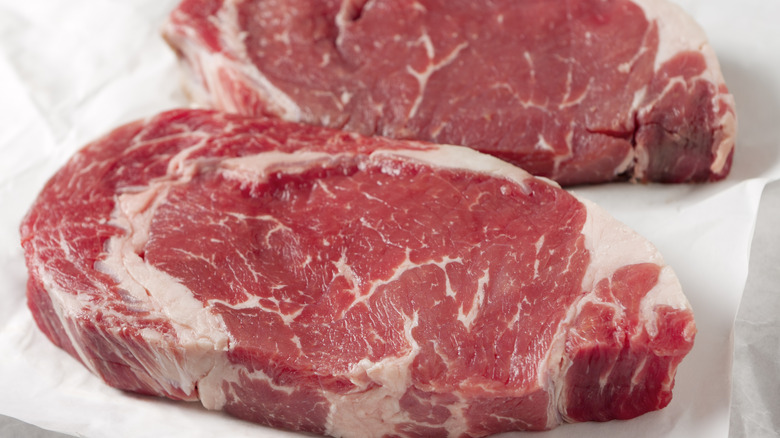 Two raw ribeye steaks on butcher's paper