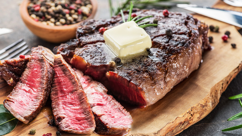 Grilled ribeye steak that has been sliced at the edge to reveal a pink center