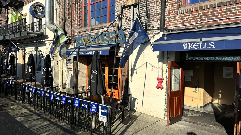 Exterior of Kells pub with blue signs on sunny day