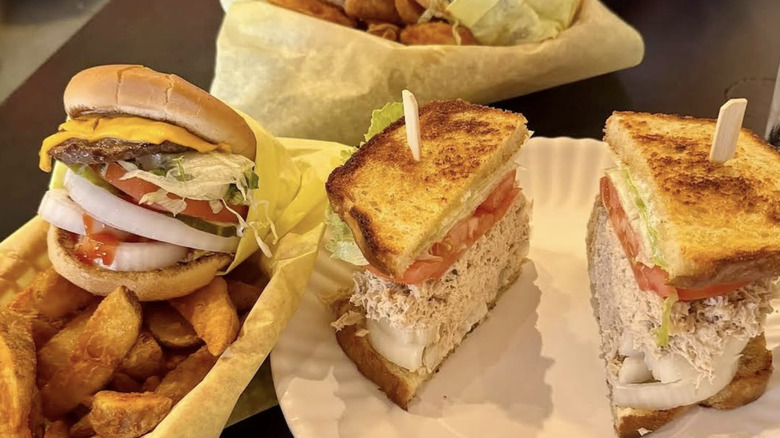 Burgers and tuna sandwiches on paper plates