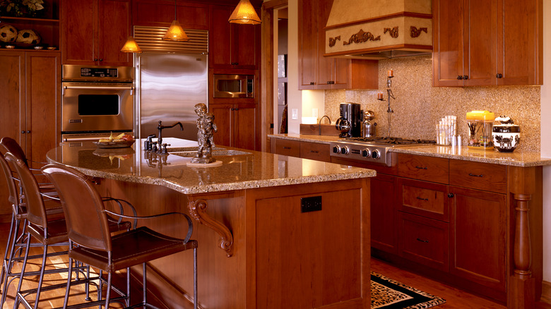 Kitchen filled with deep brown cabinetry, an island, and corresponding brown stone walls and countertops