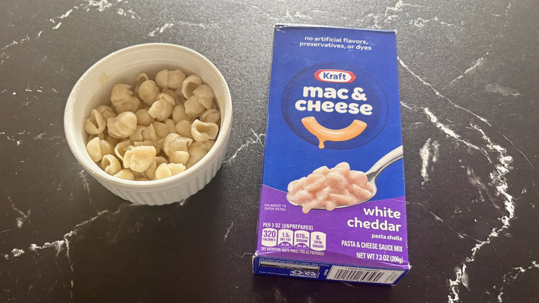 Kraft white cheddar mac and cheese box next to bowl of mac and cheese