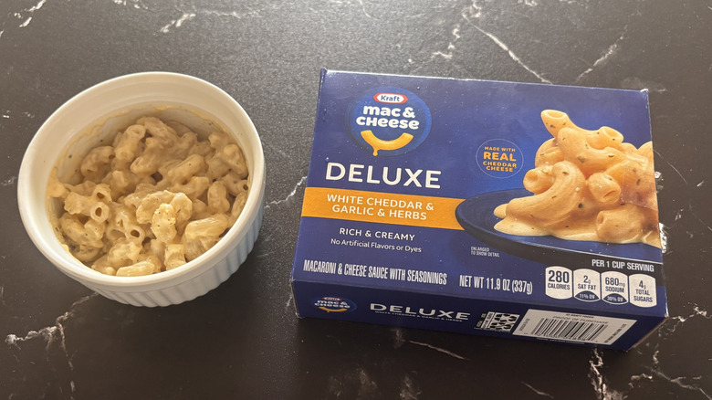Kraft deluxe white cheddar & garlic & herbs mac and cheese box next to bowl of mac and cheese