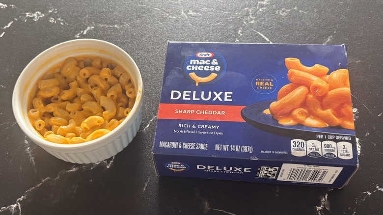 Kraft deluxe sharp cheddar mac and cheese box next to bowl of mac and cheese