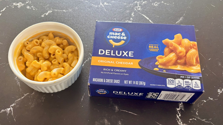 Kraft deluxe original cheddar mac and cheese box next to bowl of mac and cheese