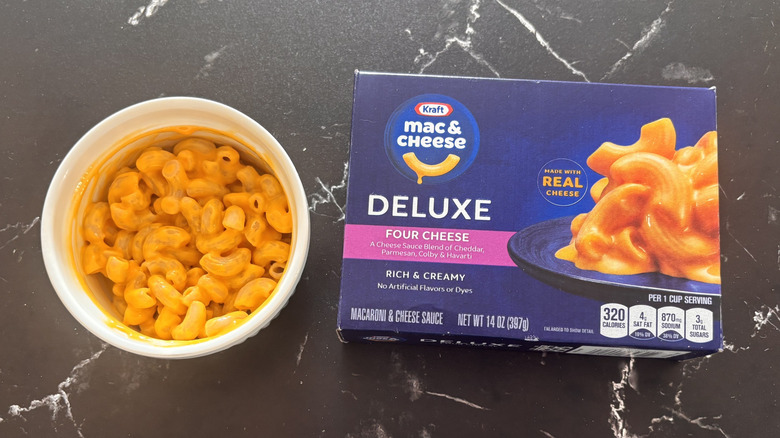 Kraft deluxe four cheese mac and cheese box next to bowl of mac and cheese
