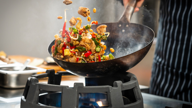 Wok filled with veggies over high heat