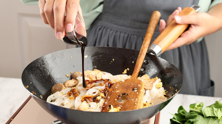 Adding sauce to a wok