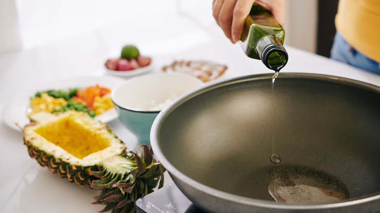 Person pouring oil into a wok