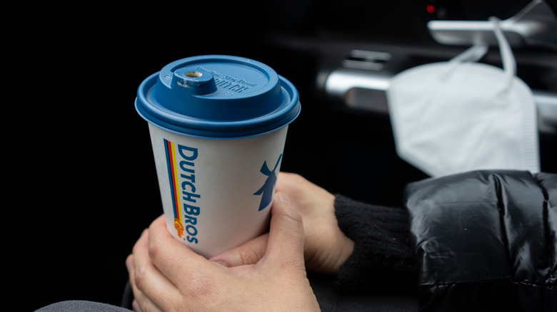 Someone holding a cup of Dutch Bros coffee in a car.