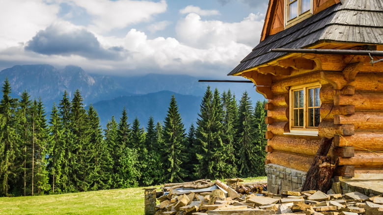 Remote cottage on the mountains, trees, mountains, and clouds in the background