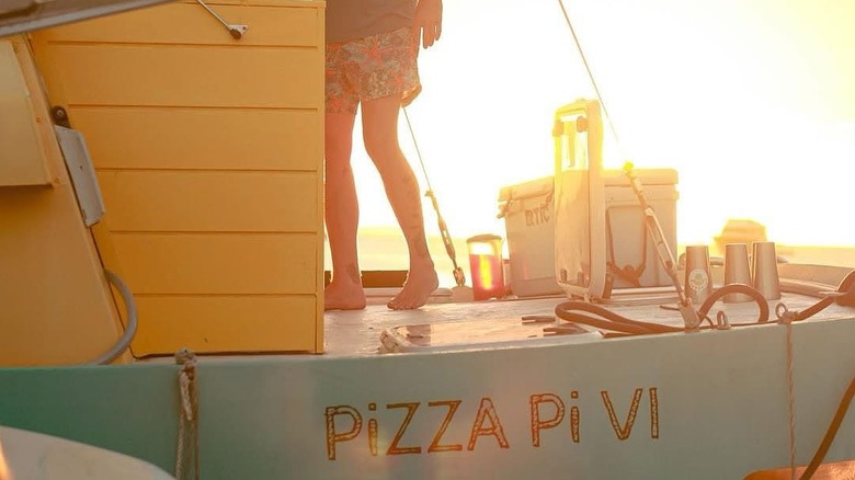Person standing on Pizza Pi VI boat during sunset